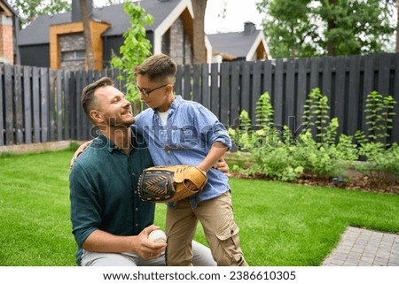 Father and son play baseball on the lawn of house