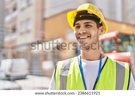 Young hispanic man architect smiling confident standing at park Royalty-Free Stock Photo #2386611921