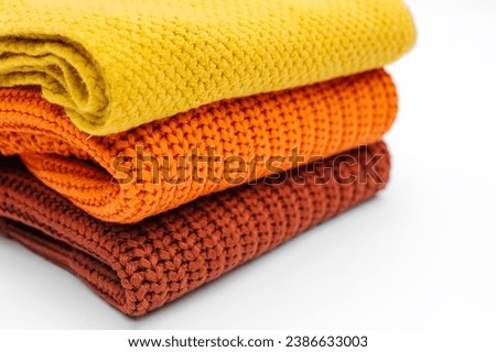 Stack of knitted sweaters and scarf  on white background. Women's warm jumpers, stylish autumn or winter clothes. Fashion autumnal outfit. Cozy bright  fall look. Royalty-Free Stock Photo #2386633003
