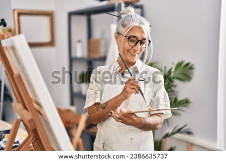 Middle age grey-haired woman artist smiling confident drawing at art studio