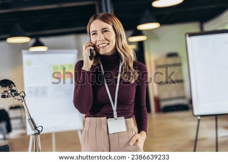 Smiling businesswoman standing in modern office talking on the phone