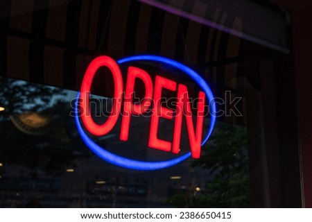 Open sign glows in the front window of a shop.