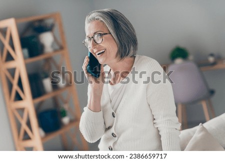 Photo of adorable sweet senior lady dressed white cardigan eyewear talking apple samsung iphone modern gadget indoors house room