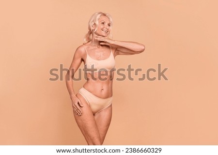 Photo of charming lovely lady dressed trendy bra panties touch face chin look empty space isolated on beige color background