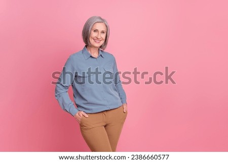 Portrait of confident cheerful person with gray short hair wear stylish shirt standing hold arms in pockets isolated on pink background