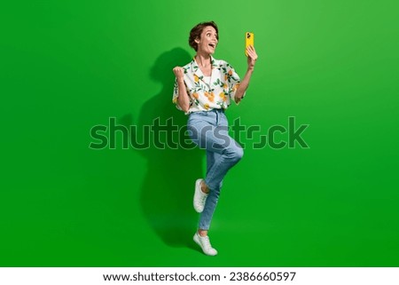 Full body photo of overjoyed young girl raised fist up using smartphone receive email approved new job isolated on green color background