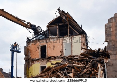 Dismantling and destruction of an old building with the help of an excavator. Part of the building is destroyed. View from below