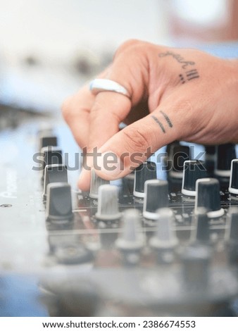 Crop anonymous tattooed sound master with silver ring working on professional equipment for creating music at disco party