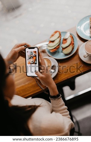 Anonymous female taking photo of fresh coffee and snacks while sitting at table in cafe