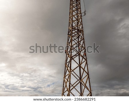 Old television and radio tower in faded colors with rusty structural members, and a cloudy sky.
 Royalty-Free Stock Photo #2386682291
