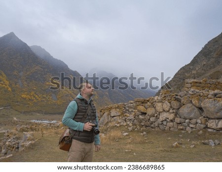 A male tourist takes pictures of a beautiful autumn mountain foggy landscape using a camera