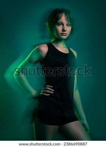 Teen girl athlete standing against green background. Green motion blur is added purposefully