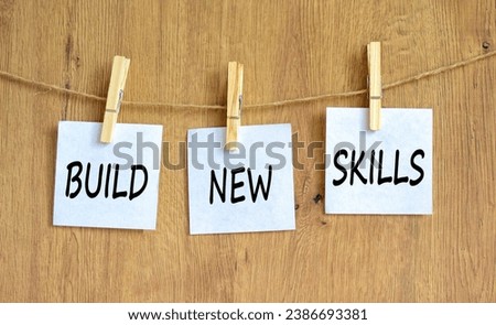 Build new skills symbol. Concept word Build new skills on beautiful white paper on wooden clothespin. Beautiful wooden table wooden background. Business, education build new skills concept. Copy space Royalty-Free Stock Photo #2386693381