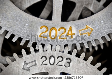 Photo of tooth wheel mechanism with numbers 2024 and 2023 and arrows imprinted on metal surface. New Year concept. Royalty-Free Stock Photo #2386718509