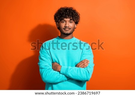 Portrait of young leader guy wearing stylish turquoise sweatshirt folded hands feel self confidence isolated on orange color background