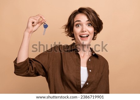 Photo of impressed funky lady wear brown shirt holding new home keys isolated beige color background