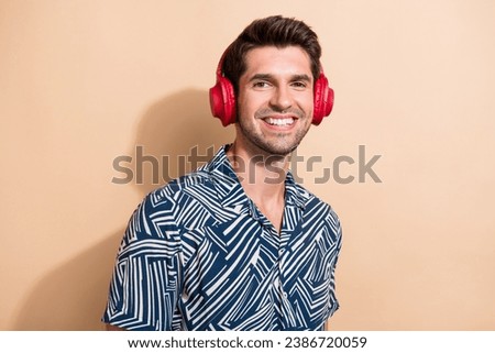 Photo of nice positive man dressed stylish clothes listening playlist mp3 player isolated on beige color background