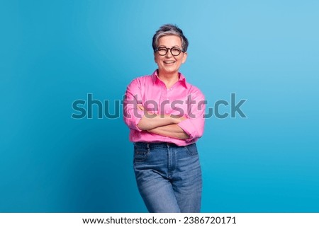 Portrait of good mood person with grey hairdo wear stylish blouse in eyewear holding hands crossed isolated on blue color background