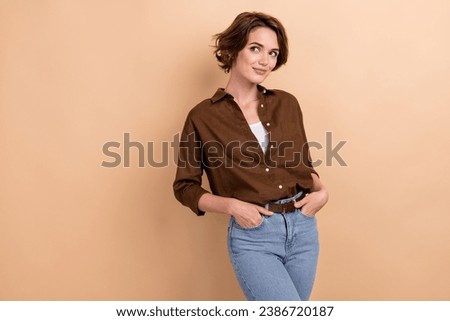 Portrait of gorgeous girl with short hairdo wear stylish shirt palms in pockets look empty space isolated on beige color background