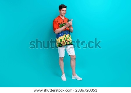 Full length photo of clever man with stylish hairdo dressed print shirt look at smartphone read email isolated on blue color background