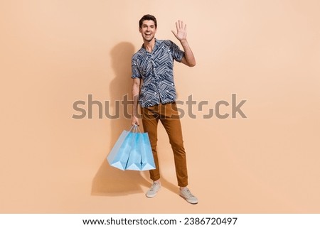 Full length photo of friendly boyfriend hold packages invites you visit zara home boutique waves palm isolated on beige color background