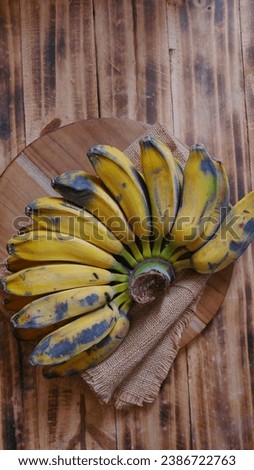A comb of cooking banana, it's well known in Indonesia called "pisang kepok kuning"  on wooden table 