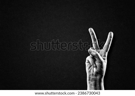 Hand Showing Peace Victory Sign in Black and White on Textured Paper Background, Copy Space