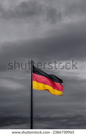 Germany flag waving in the wind close-up against a blue sky. German flag on contrasting sky
