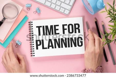 Time for planning. Green plant, a cup of coffee next to a pen and a notebook that says TIME TO PLANNING on a pink table. Flat lay.