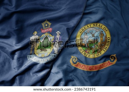 big waving colorful national flag of idaho state and flag of maine state . macro