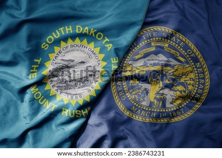 big waving colorful national flag of nebraska state and flag of south dakota state . macro