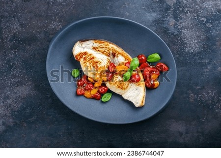 Roasted swordfish steak with tomatoes and paprika served as top view on a design plate Royalty-Free Stock Photo #2386744047