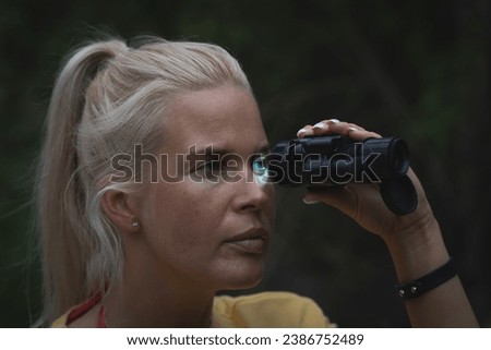 A girl looks through a night vision device at dusk in the forest. High quality photo