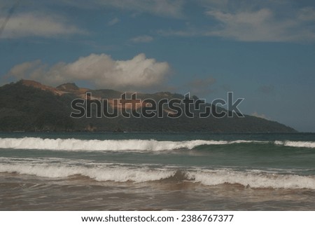 beach with calm waves and hill views in the daytime
