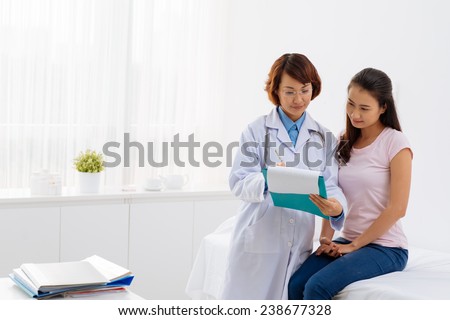 Young doctor showing her patient life insurance policy Royalty-Free Stock Photo #238677328