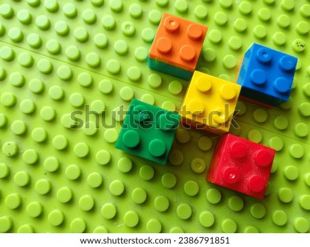 Colorful and colored stackable plastic toy bricks on green background. Childhood education construction concept