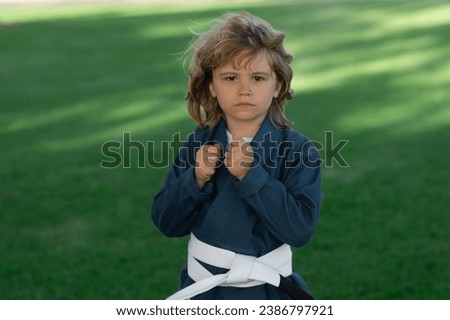 Kid boy practicing martial arts outdoor. Sport karate kids. Little boy wearing kimono doing karate in park. Child training martial arts. Little martial arts fighter. Martial arts for kids. Royalty-Free Stock Photo #2386797921