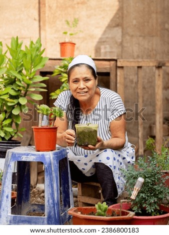 Adult woman, surrounded by flowerpots and plants, looking and sm