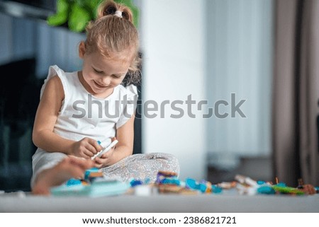 Smiling Little girl playing with small constructor toy on the floor in home living room, educational game, spending leisure activities time concept. High quality photo