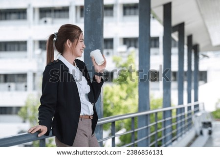 Portrait of a confident Asian businesswoman standing with a coffee cup on a skywalk in the morning. smiling and be happy to start work.