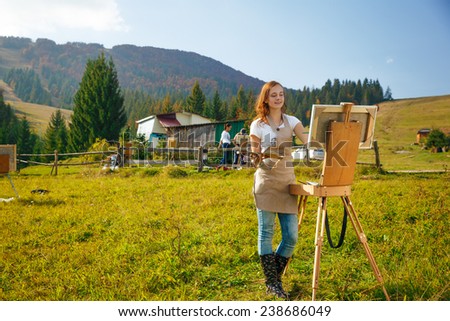 Young painter at work in the mountains with palette