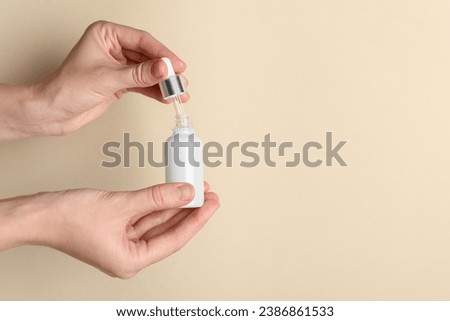 Woman with bottle of cosmetic serum and dropper on beige background, closeup. Space for text