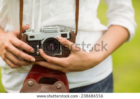 Mid section of woman holding vintage camera in the park