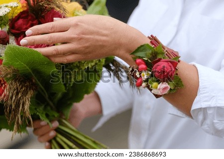 A close-up of a bouquet of autumn flowers and a bracelet on the hand of flowers. The concept of floristry.