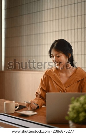 Smiling young businesswoman working on investment and marketing projects at modern office.