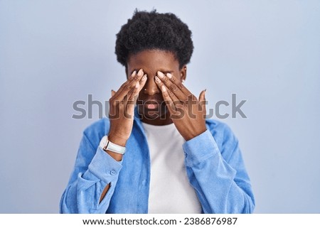 African american woman standing over blue background rubbing eyes for fatigue and headache, sleepy and tired expression. vision problem 