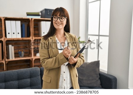 Young beautiful hispanic woman business worker writing on document at office