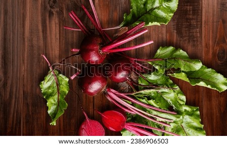 Red Beetroot with herbage green leaves on wooden rustic background. Organic Beetroot. Top view. Royalty-Free Stock Photo #2386906503