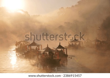 A bird's-eye view of people riding traditional Chinese boats in the morning mist at Ban Rak Thai Royalty-Free Stock Photo #2386915457