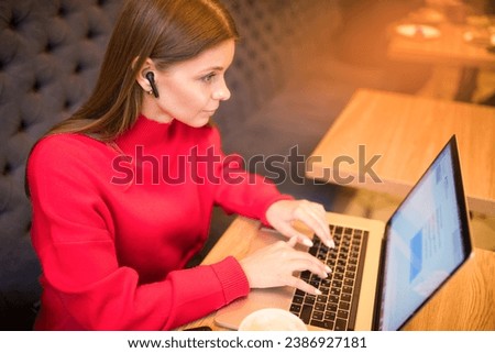 Woman skilled resume writer keyboarding on laptop computer while sitting in restaurant with cup of coffee. Female forex trader received e-mail on notebook gadget 